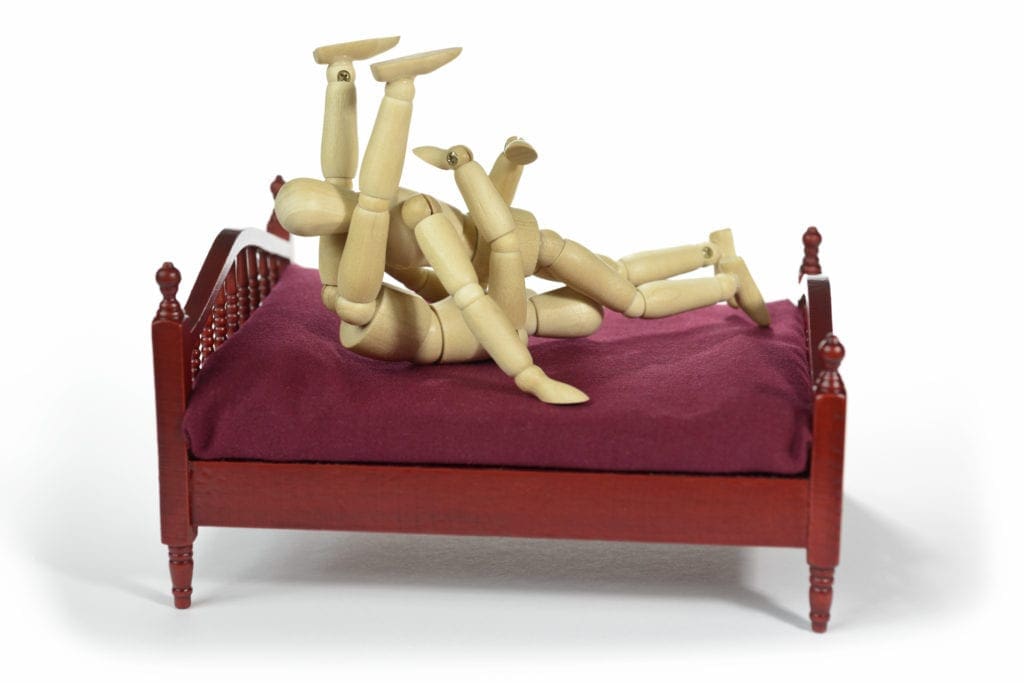 Wooden figures during sex in the bed. 69 position in the bed.